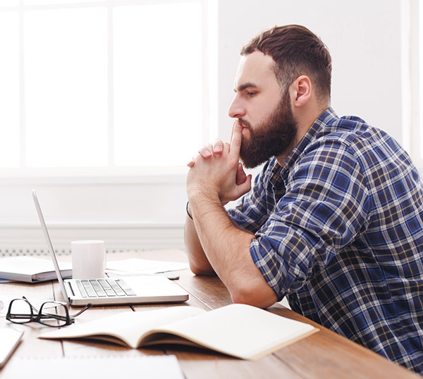 Stressed pensive businessman in office. Casual young man employee at work with laptop, job problems concept. Lifestyle portrait